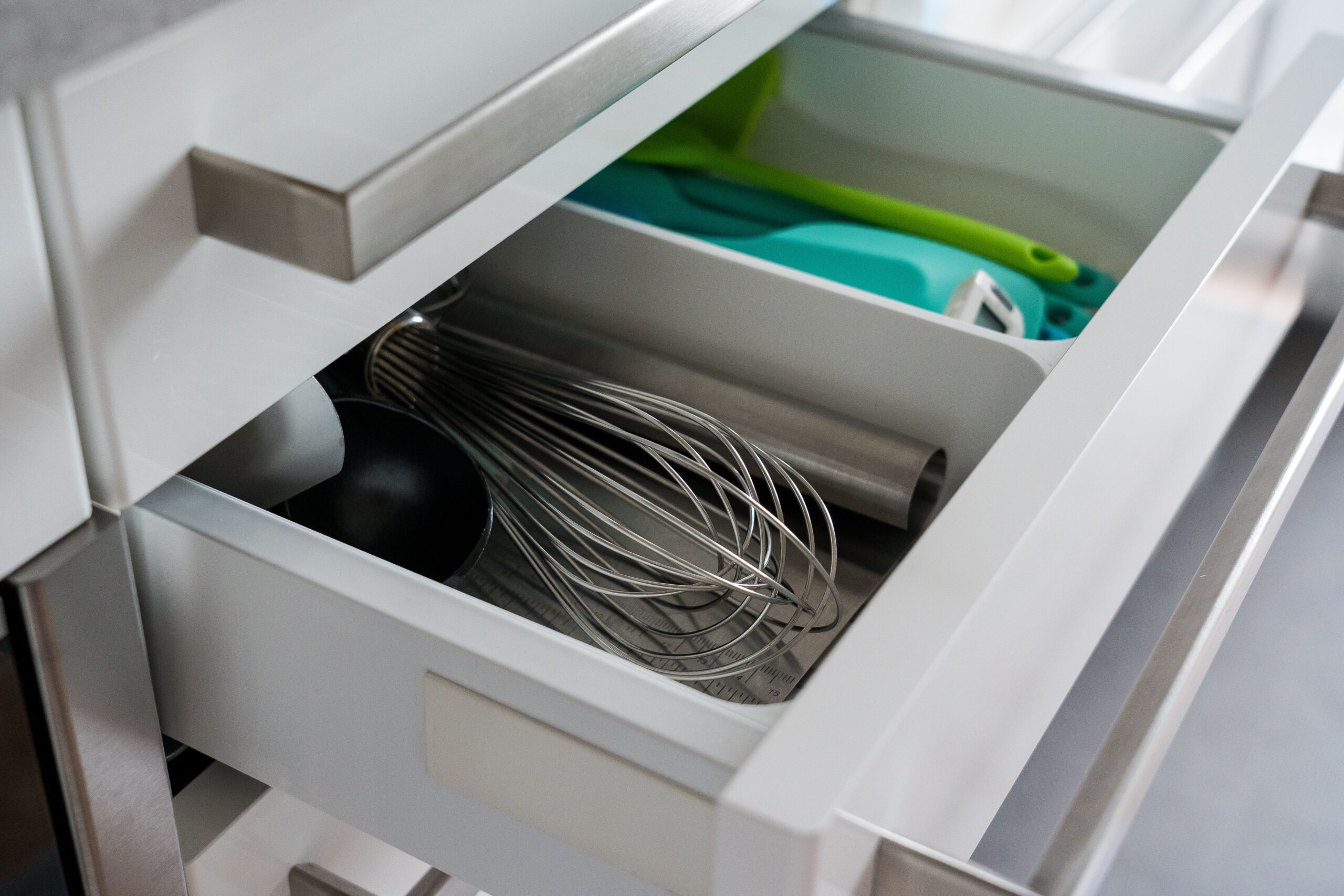 Neatley organized kitchen drawer with whisks and everyday utensils sorted by use