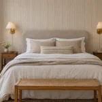 Renter-friendly bedroom ideas: a small bedroom with a peel-and-stick wallpaper accent wall, a freestanding headboard, and plug-in wall sconces
